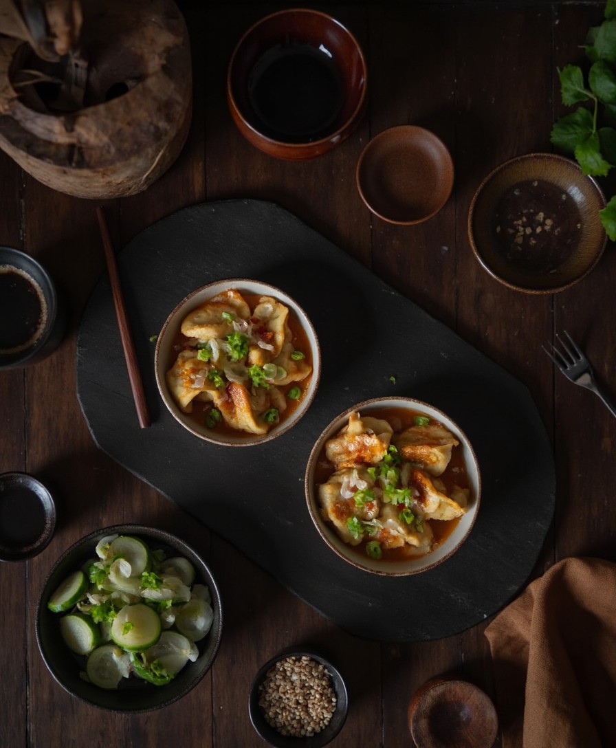 Dumpling Lasagne Tischszene von oben mit zwei Portionen, Gurkensalat, Sojasauce und Sesam-Dip